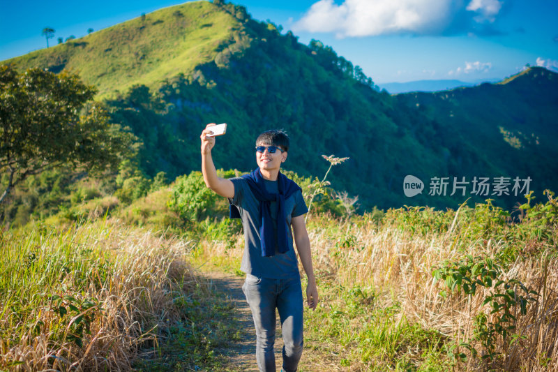 年轻的旅行者站在山上望着夕阳。