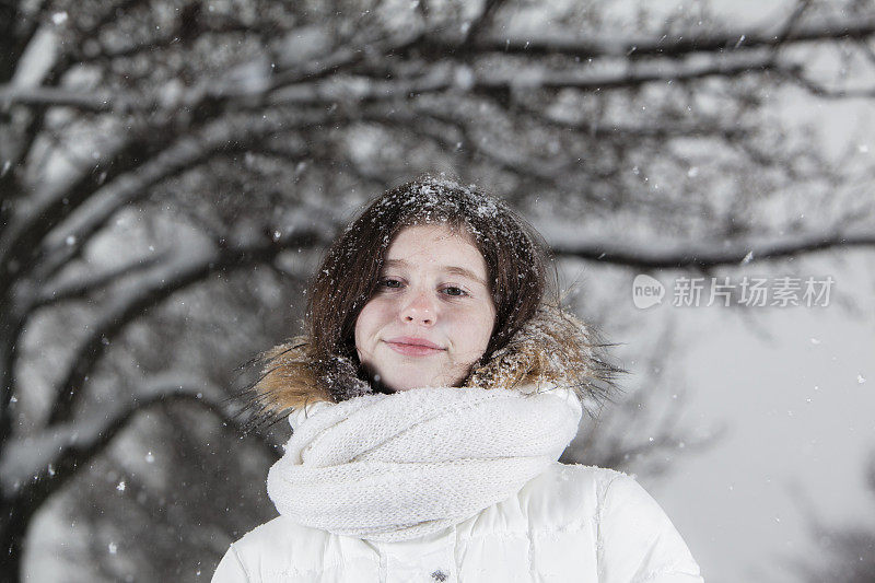 雪下穿着白色夹克的漂亮少女