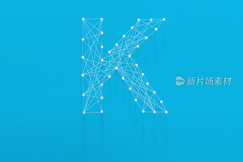 字母'K'由别针和字符串在孤立的背景