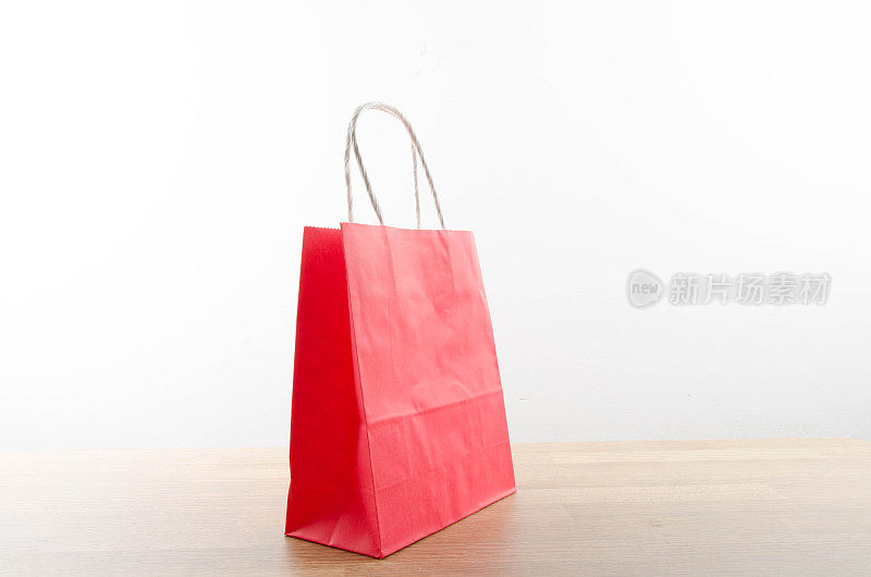 红色购物袋放在一张木桌上