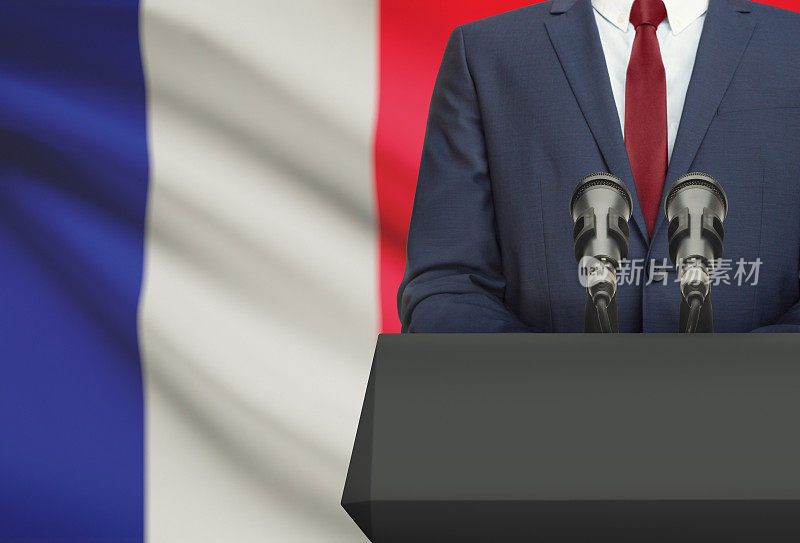 商人或政治家在讲坛后面发表演讲，背景是法国国旗