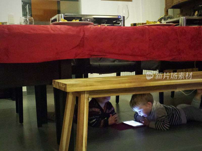 孩子们在桌子下面玩平板电脑