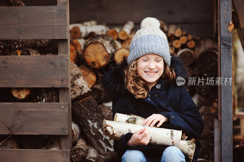 快乐的童女在冬天或秋天从棚子里捡柴火