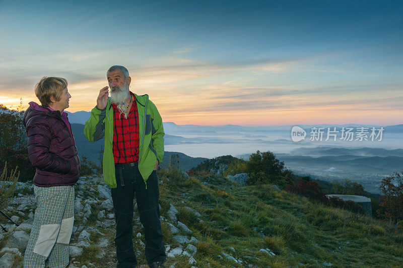 快乐的老年夫妇远足在秋天的黎明在朱利安阿尔卑斯山，斯洛文尼亚，欧洲