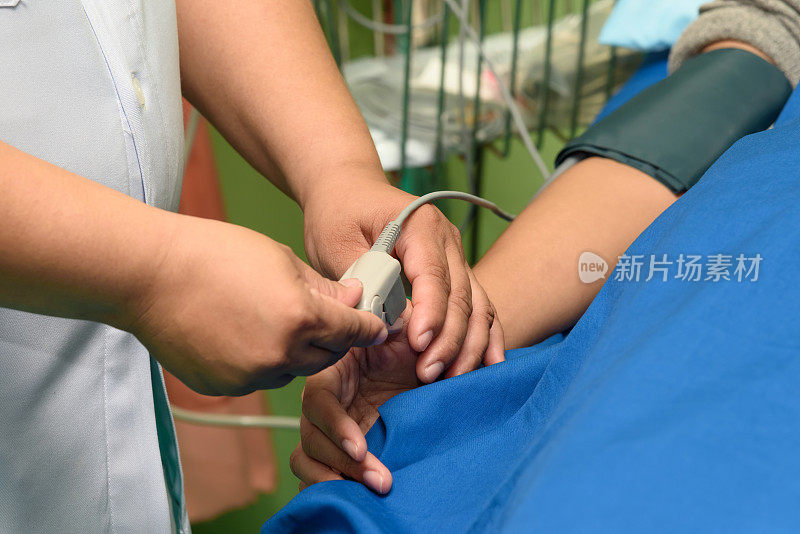 医生在病人手上使用脉搏血氧计传感器