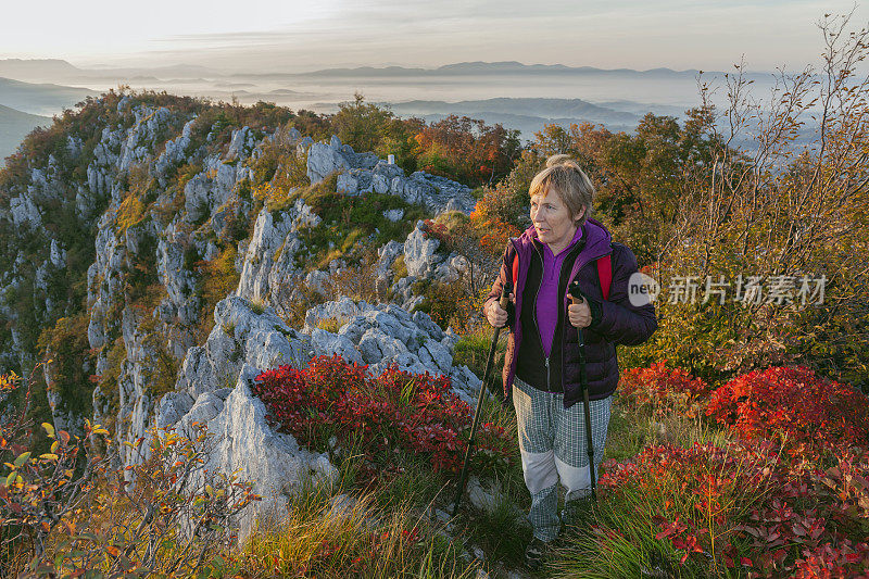 快乐的年长妇女徒步在秋天的黎明在朱利安阿尔卑斯山，斯洛文尼亚，欧洲