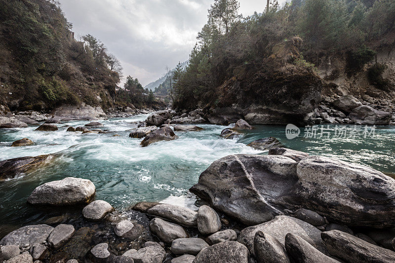 在尼泊尔，多云的日子里，一条河流流经Pakding山谷