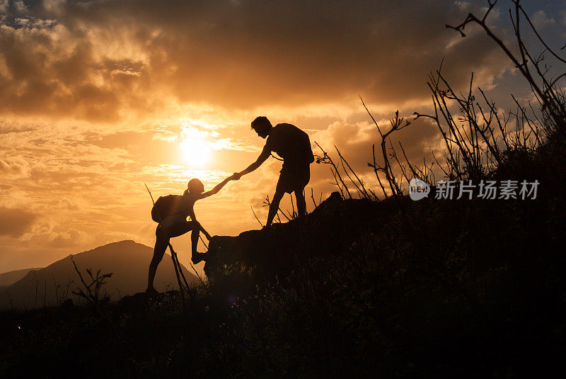 日出时，人们互相帮助爬山。