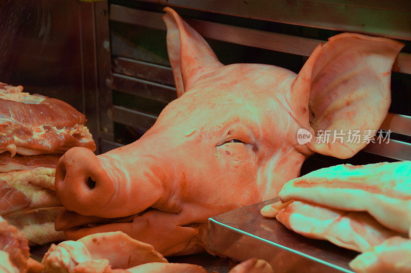 在零售展示中被肉包围的生猪头。