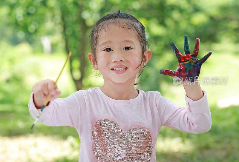 可爱的小女孩画着双手在公园里，教育艺术理念。
