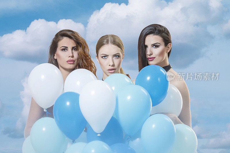 三个年轻女人拿着一堆氦气蓝色的气球顶着天空夏天的时尚