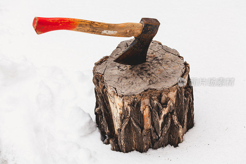 斧头在白雪上伸出树桩