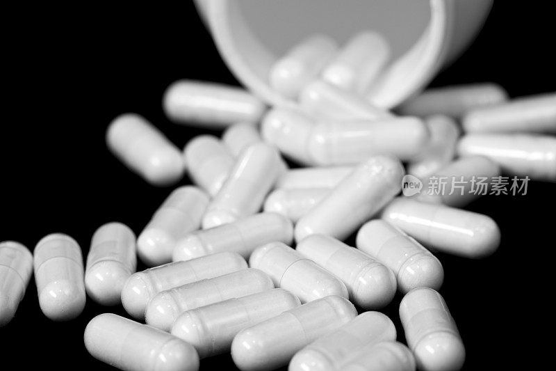 药物特写，白色胶囊和药瓶黑白相间