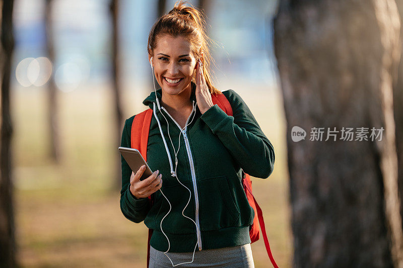 年轻的女运动员在大自然中听音乐