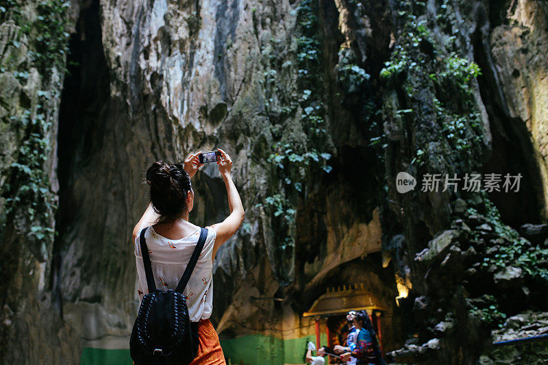 在马来西亚的巴图洞穴独自旅行的女人，用她的手机拍照