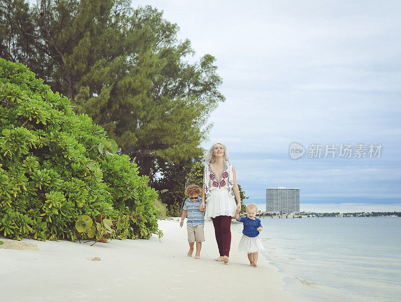 一个白人家庭在海滩上走向摄像机。