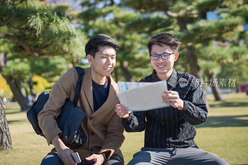 年轻的亚洲男子和日本朋友寻找旅游地点使用手机和花时间在亚洲旅行