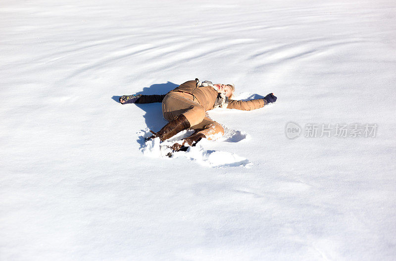 女人躺在阳光明媚的新雪