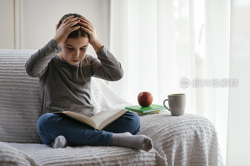 一个十几岁的女孩在窗边看书