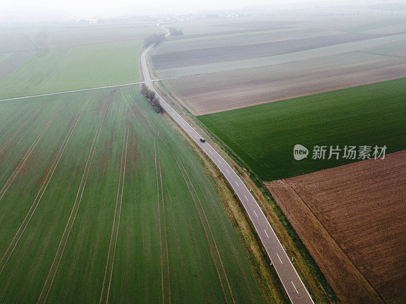 汽车鸟瞰图在雾蒙蒙的道路和丰富多彩的田野在德国