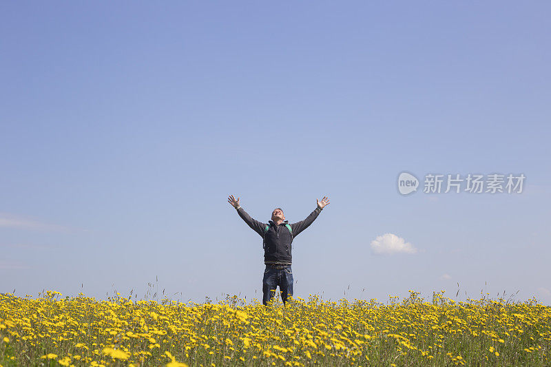 成年徒步旅行者喜欢在春天在美丽的花草地徒步旅行。