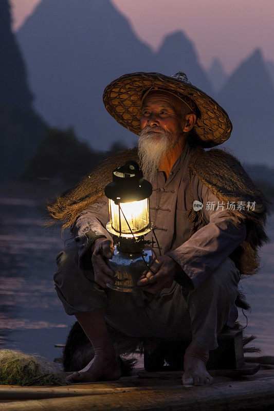肖像鸬鹚渔民在日落使用传统的捕鱼方法捕捉鱼在河里