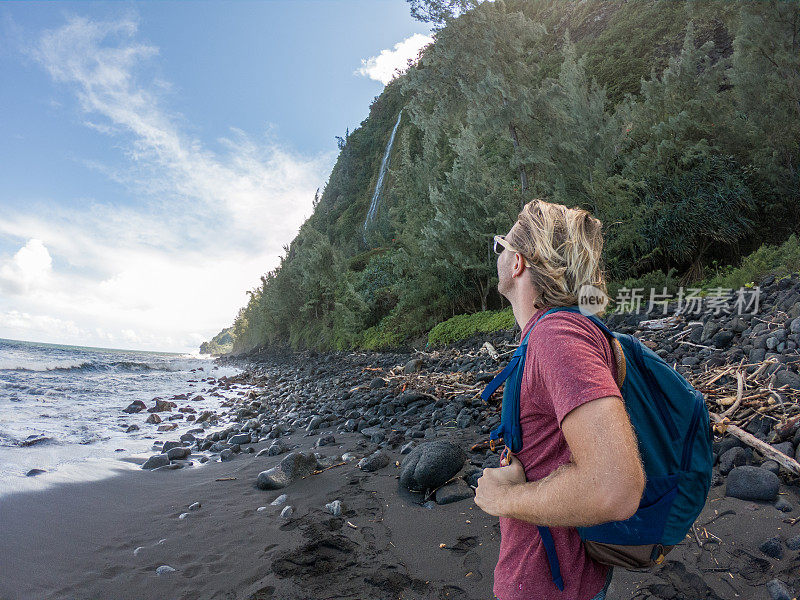 夏威夷，一名徒步旅行的男子凝视着瀑布