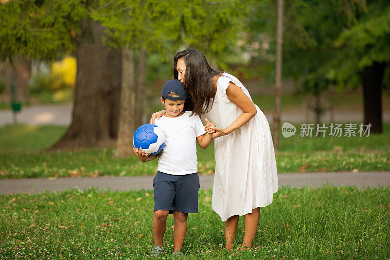 一位母亲正在公园里和她的儿子玩球。亚洲母亲和儿子踢足球