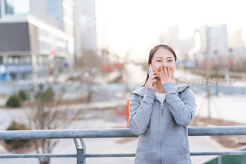 亚洲年轻女子在城市公共广场使用手机