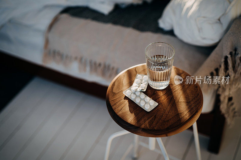 床边的桌子上放着一杯水和药片