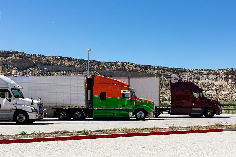 三辆不同品牌的大卡车在停车场排成一排