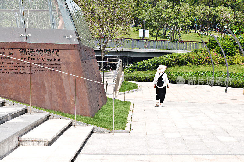 一名游客带着“人才故事集锦”(“人才体验馆”)走过位于中国深圳的人才园区的人才之星桥。深圳湾主题公园与深圳湾公园和深圳湾体育中心相连。