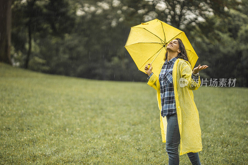 快乐的女人微笑着行走在雨天