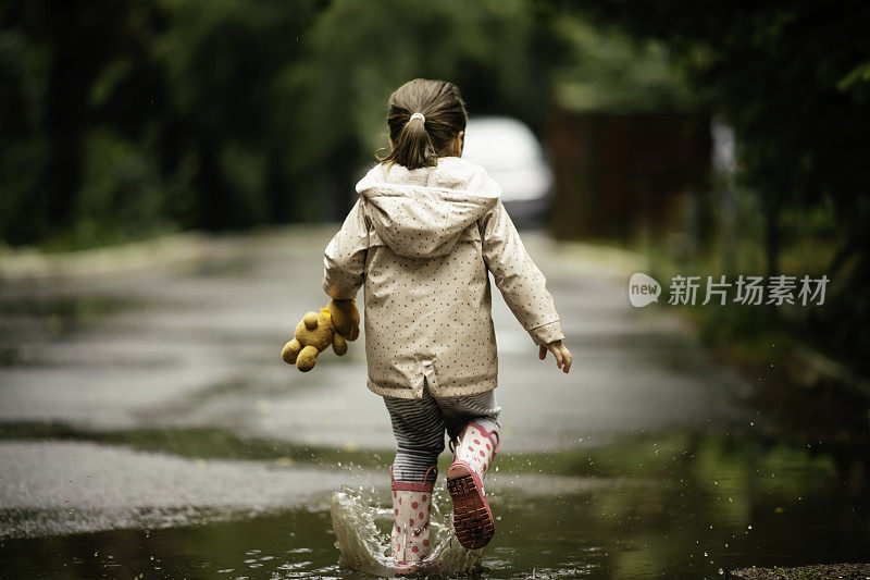 快乐的小女孩在雨中跳跃的照片