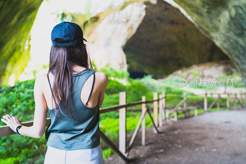 女游客张开双臂站在瀑布旁