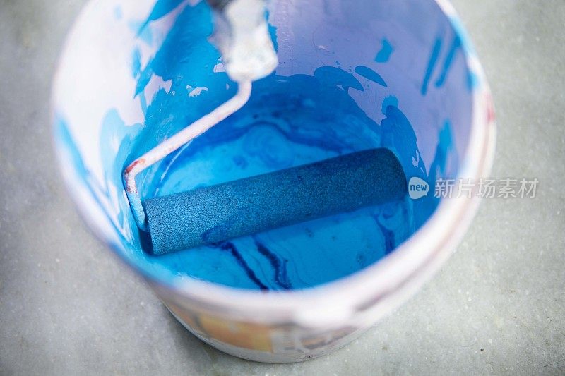 带漆辊的蓝色漆桶。