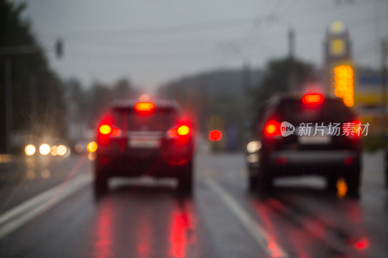 在雨后从道路上看的晚上街道汽车交通的散焦图片。