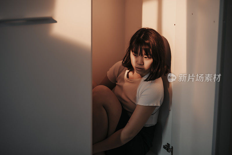 亚洲中国少女悲伤隐藏自己在衣柜晚上