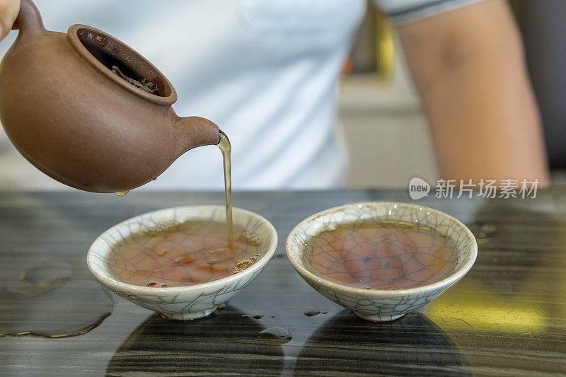 一名亚洲男子用中国传统茶具倒茶