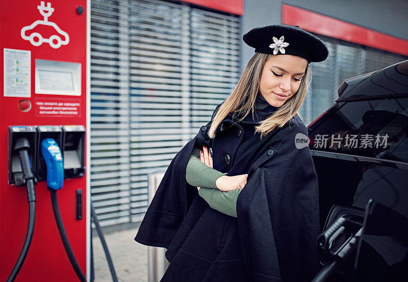 一名年轻女子在充电站为她的电动汽车充电