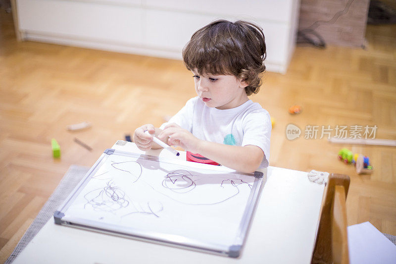 漂亮的小男孩在白板上画画。