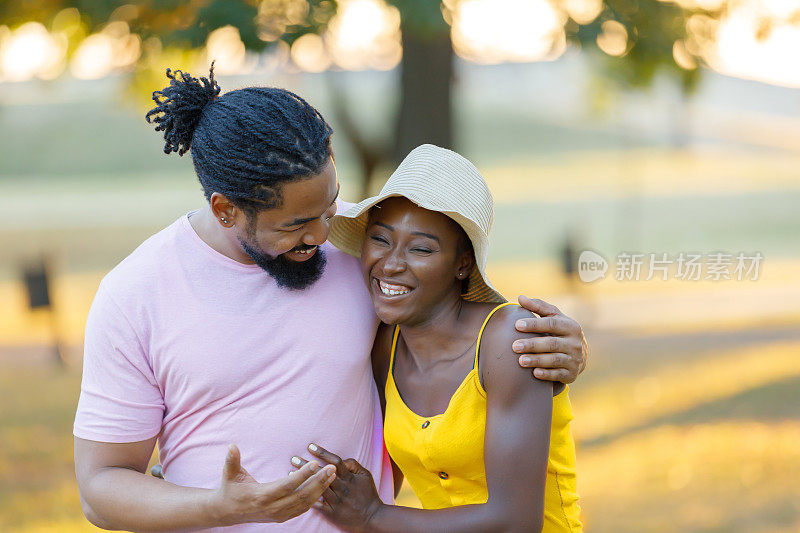 年轻的非洲裔美国男子和他可爱的妻子在公园散步。