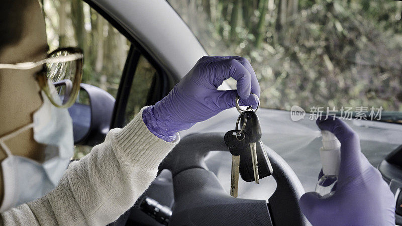 一名西班牙裔年轻女子在汽车钥匙上喷洒酒精以预防病毒