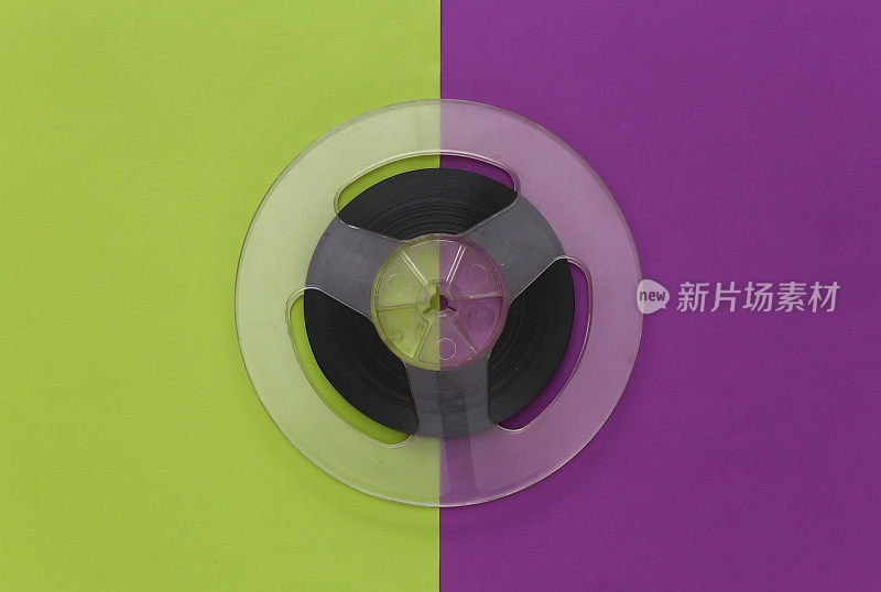音频磁带。紫绿色背景上的胶片卷轴。前视图。复古的风格。80年代