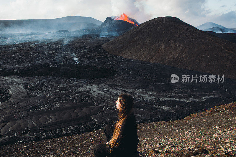 一名年轻的游客正在欣赏冰岛Fagradalsfjall火山喷发时熔化的熔岩的壮观景象