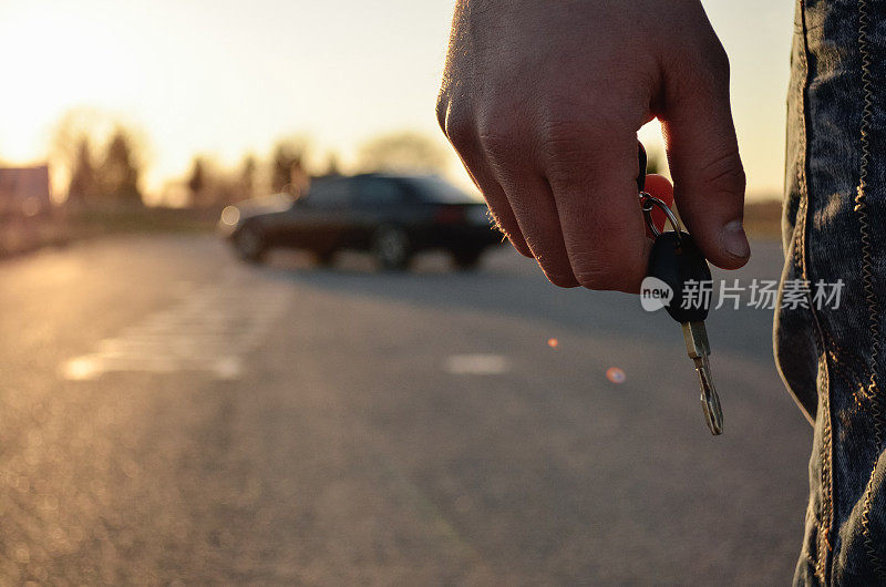 特写:一个男人的手拿着车钥匙。那个人后面的车