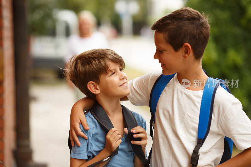 两个小学生背着书包拥抱在一起。