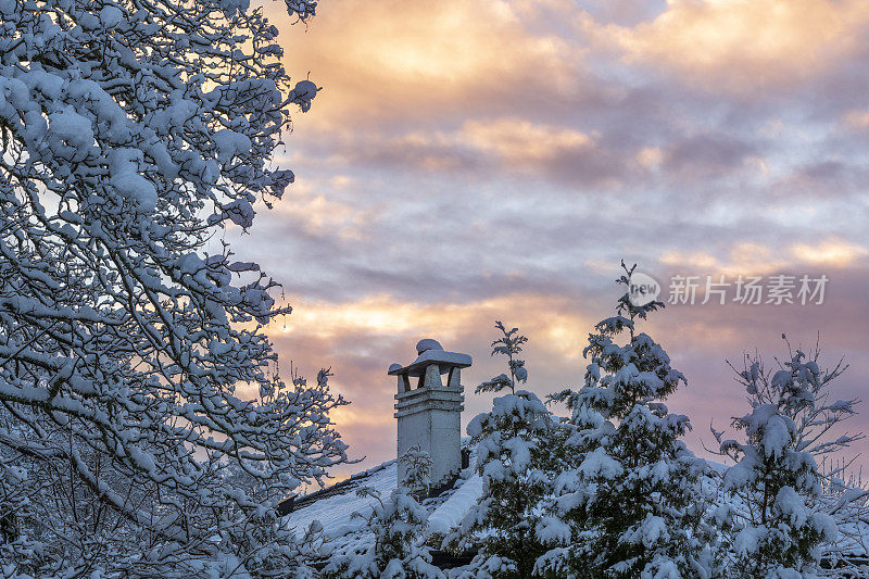 在初冬的清晨，太阳升起时，屋顶和树上覆盖着积雪