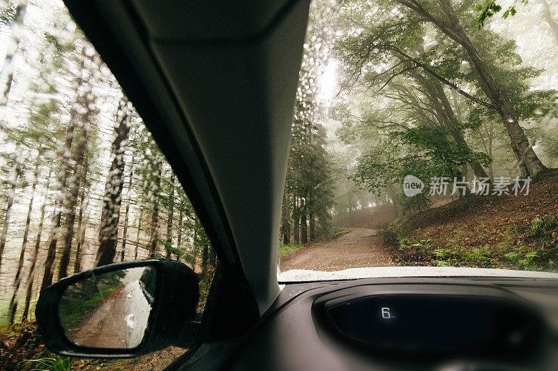 下雨天在森林道路上行驶的汽车