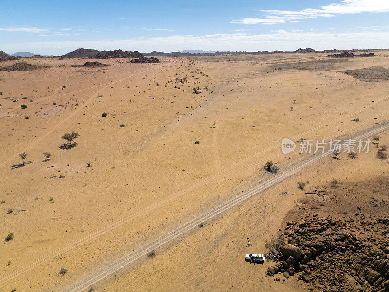 停放的车辆与土路穿过干旱的景观